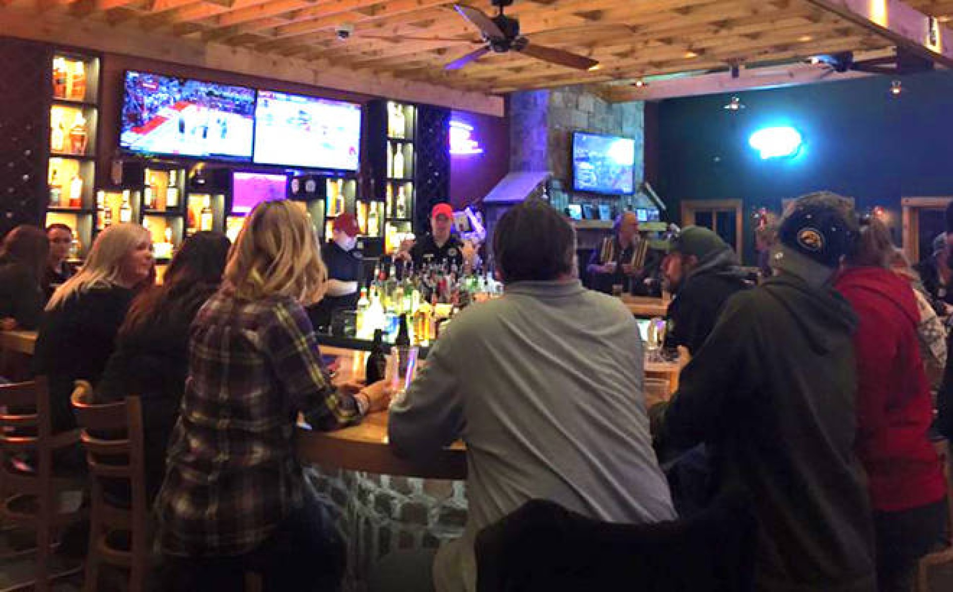 Diners sit along the bar at Oakland Acres Golf Club, watching the game and enjoying drinks.