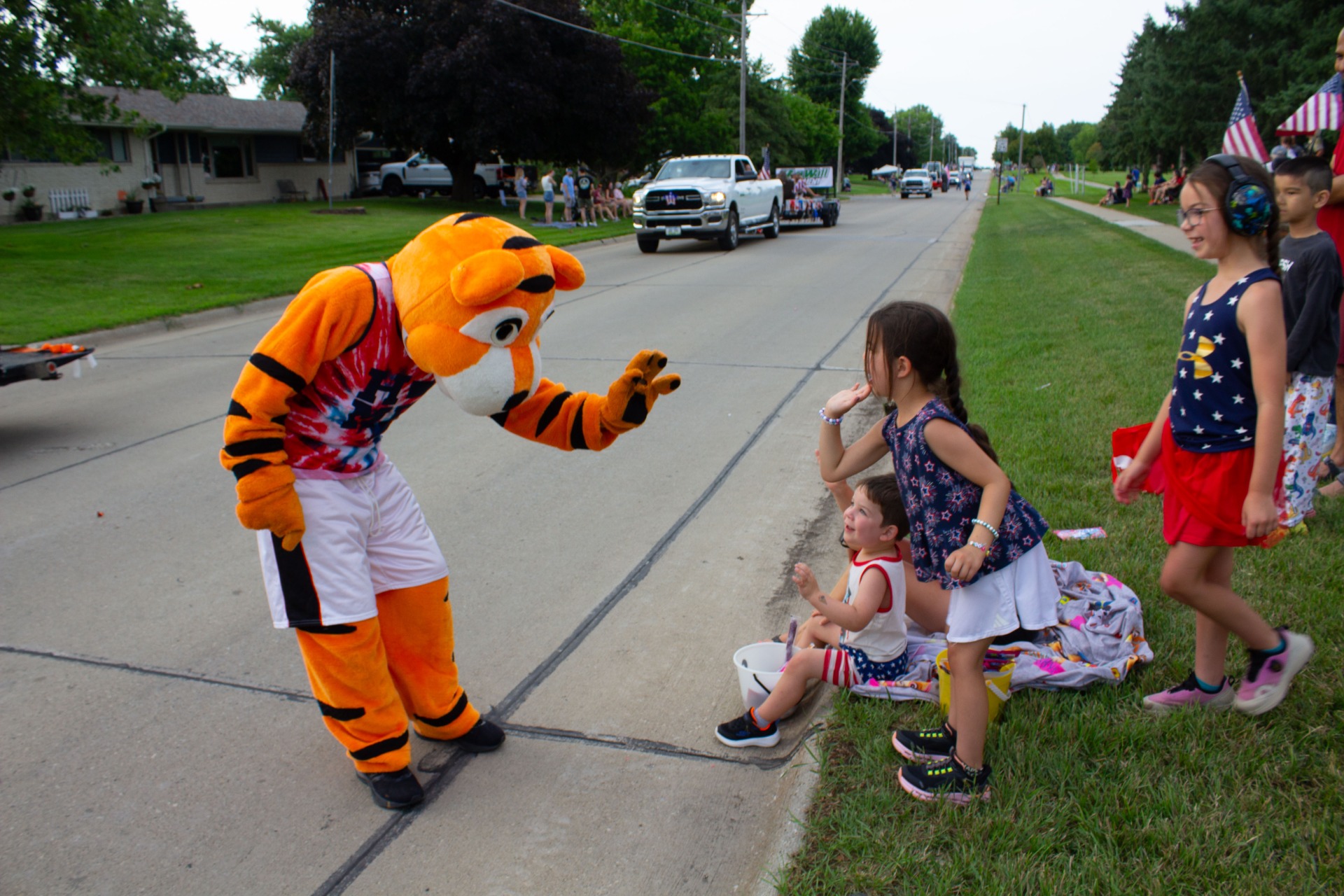 A tiger holds out his hand to high-five a tiny parade watcher.